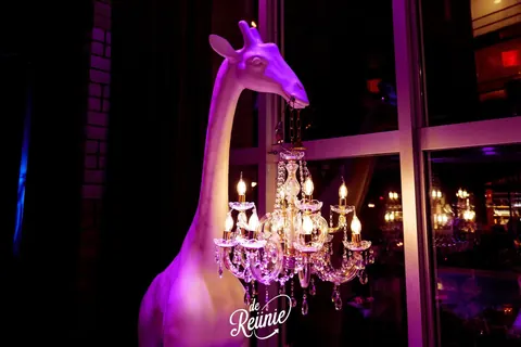 Roze giraf met kroonluchter in de club van ANNO