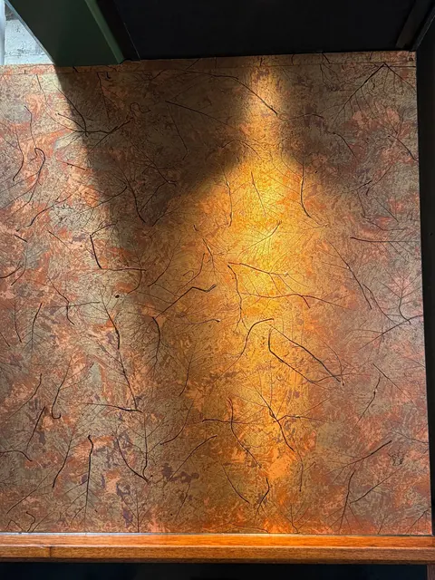 Wand met koperkleurige bladafdrukken bij ANNO Almere