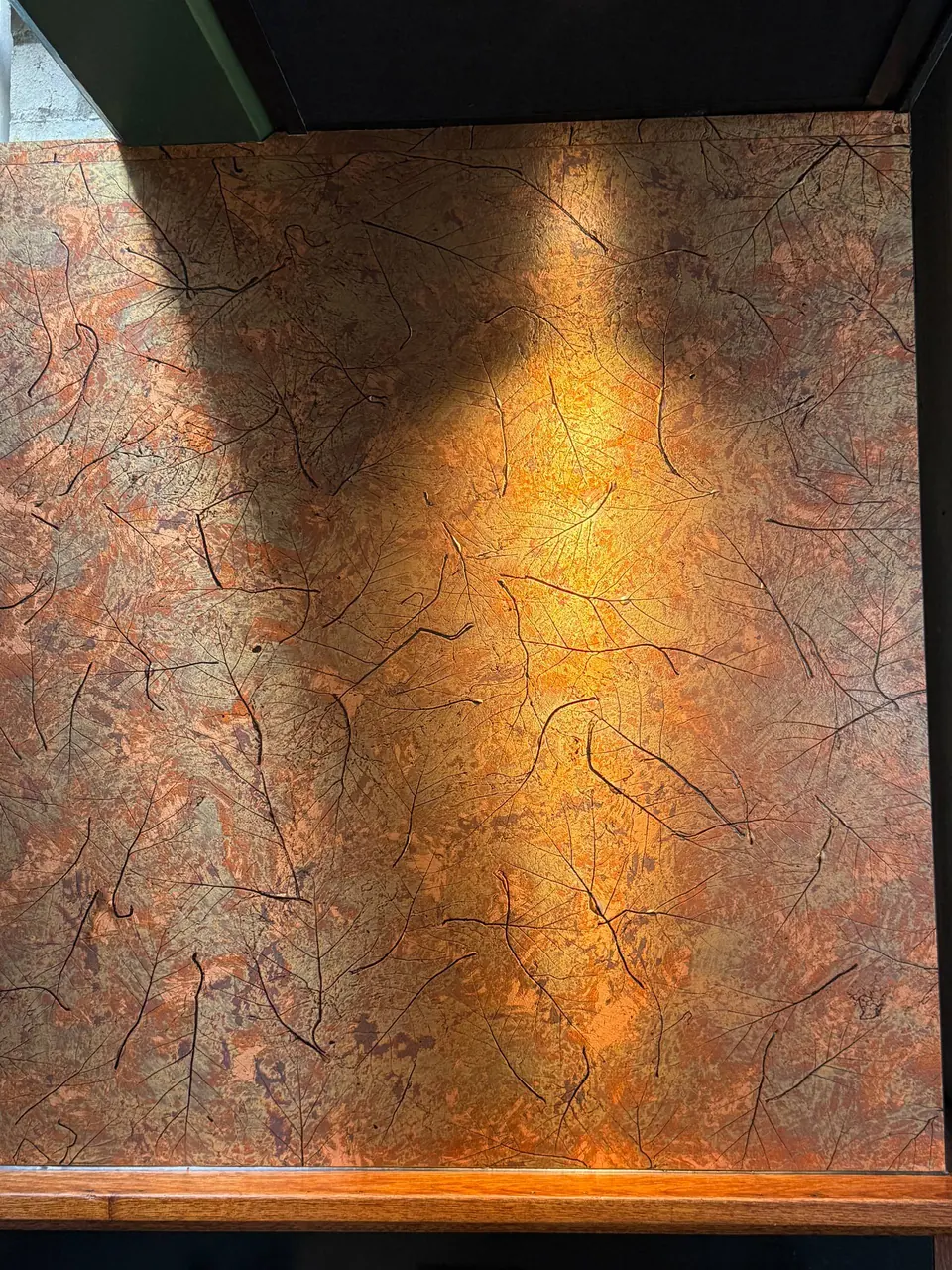 Wand met koperkleurige bladafdrukken bij ANNO Almere