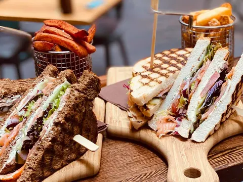 Clubsandwiches en broodjes op houten planken bij ANNO Almere