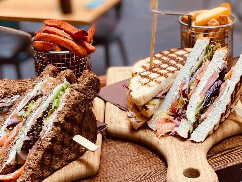 Clubsandwiches, tosti's en friet op houten planken bij restaurant ANNO Almere