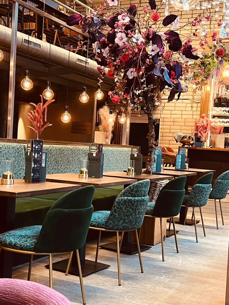 Het restaurant van ANNO overdag, met turquoise stoelen en gedekte tafels
